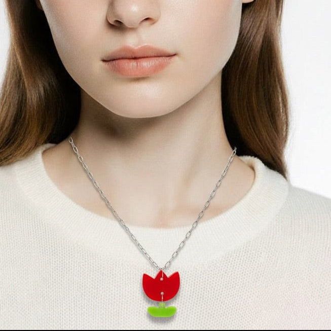 Woman wearing a necklace with a red flower pendant on a plain background