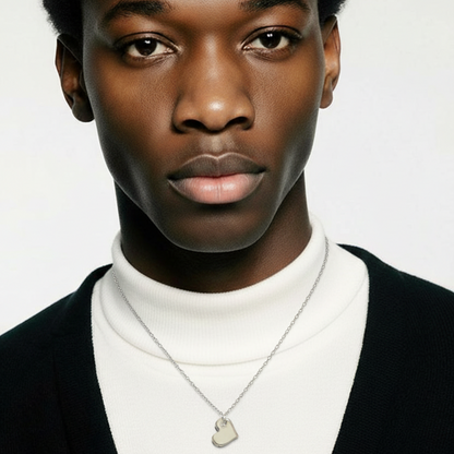 Person wearing a black cardigan over a white turtleneck with a necklace on a plain background