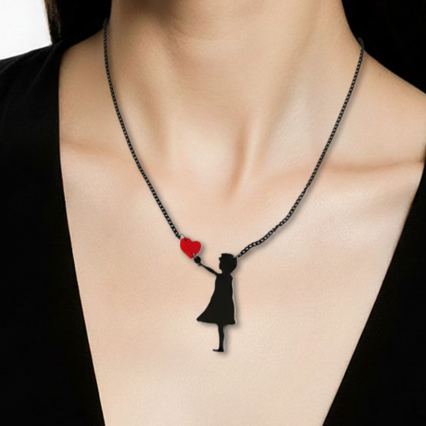 Necklace with a pendant of a woman holding a heart, worn by a person in a black top.