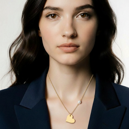 Woman wearing a gold necklace with a heart pendant against a neutral background