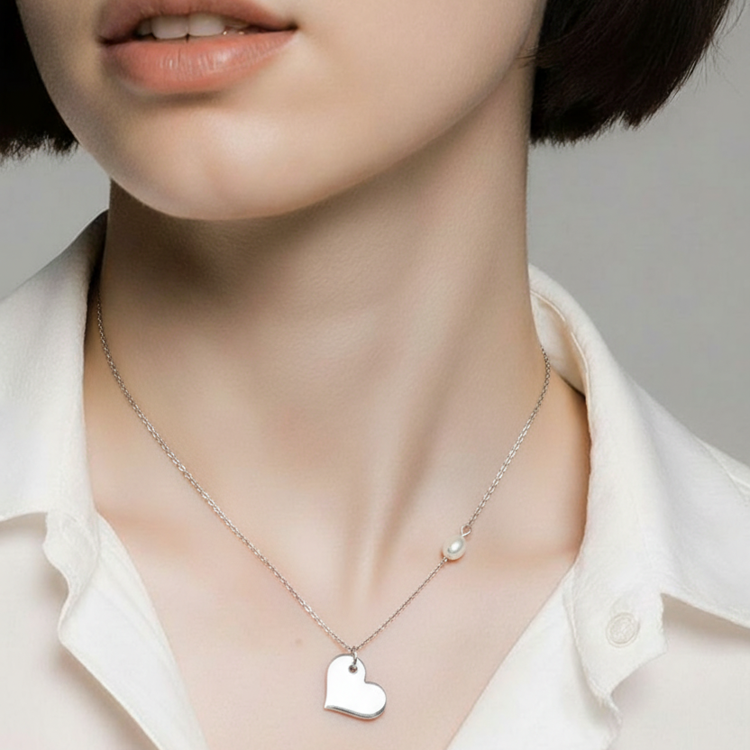 Close-up of a person wearing a silver necklace with a heart pendant on a plain background