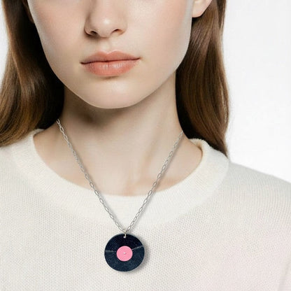 Woman wearing a necklace with a circular pendant on a plain background
